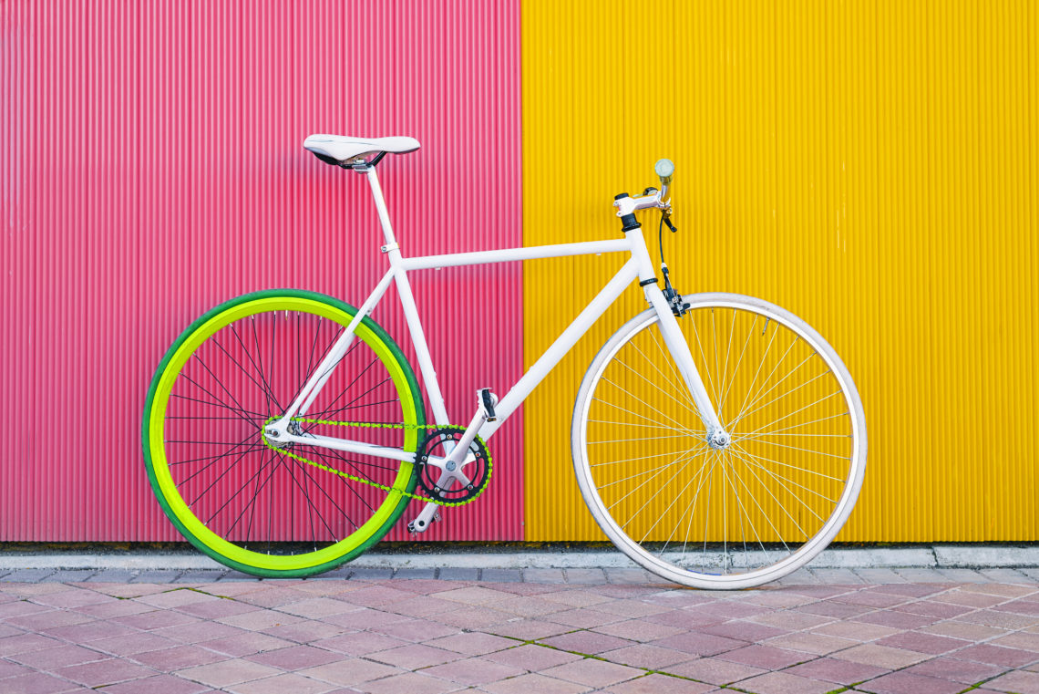 Weißes Fahrrad vor bunter Wand.